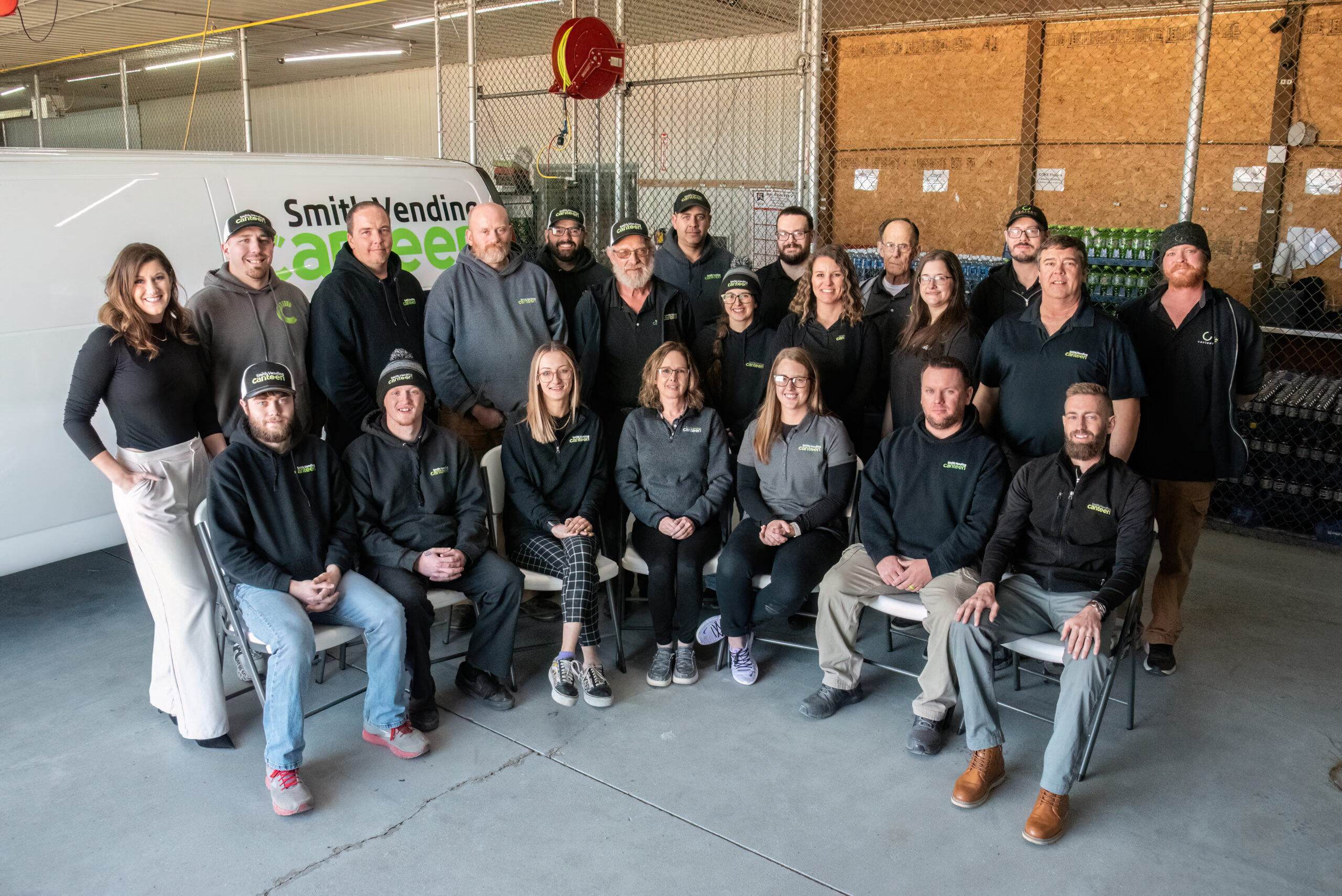 Smith Vending Canteen employees pose for a group photo in front of a van with the Smith Vending Canteen logo. 