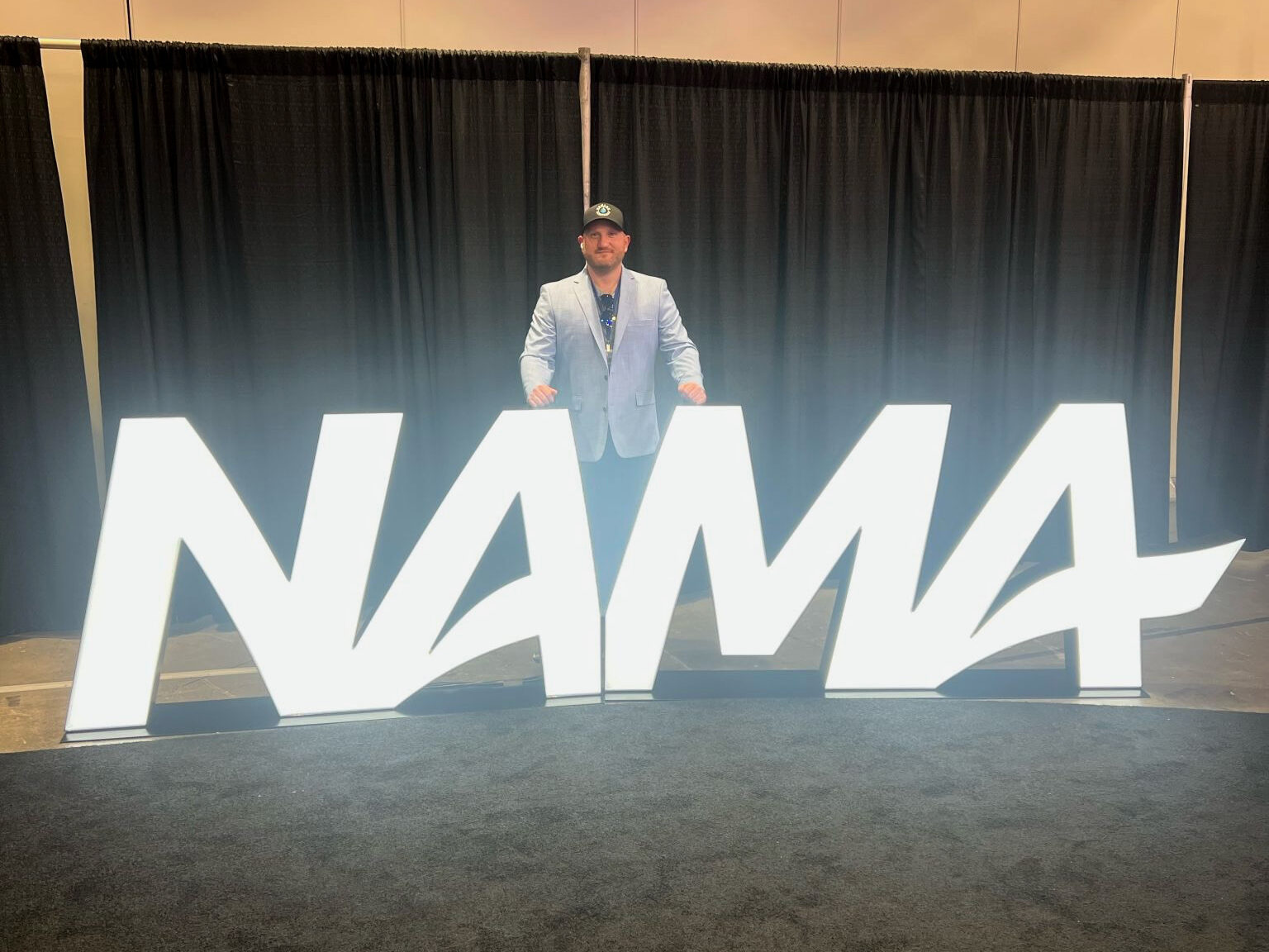 Man stands behind big glowing NAMA sign.