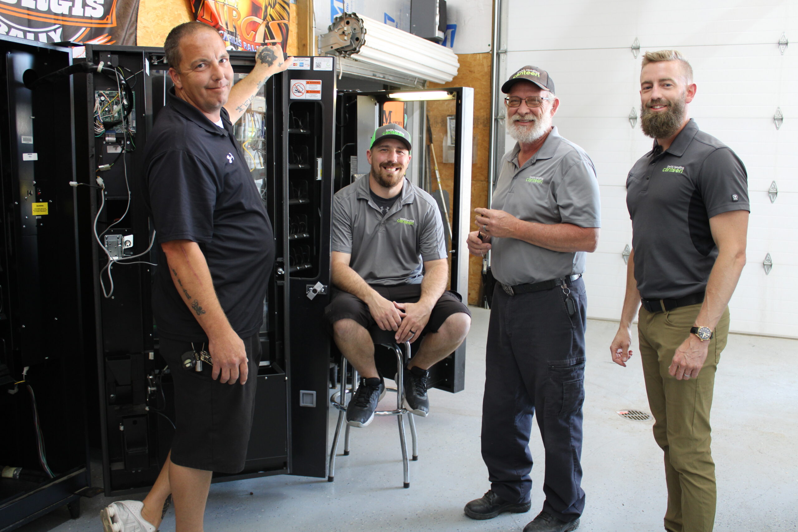 Four Smith Vending Canteen staff (men) stand in front of an open vending machine. 