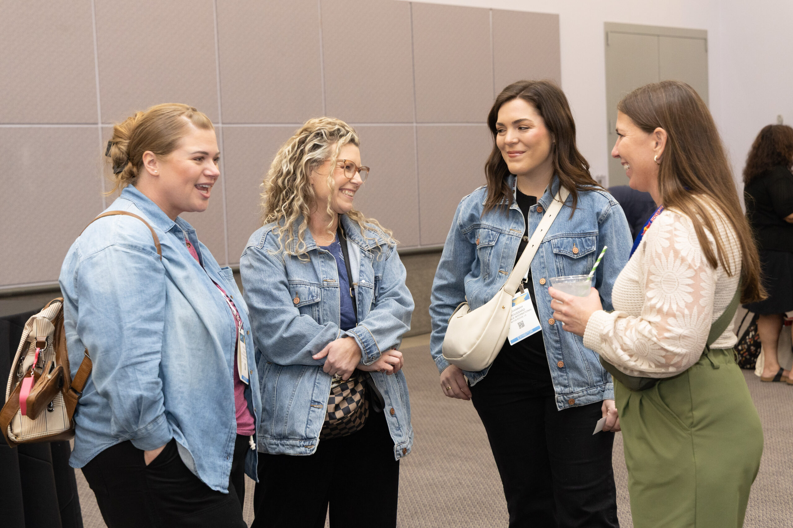 group of four women smiling at each other as they speak