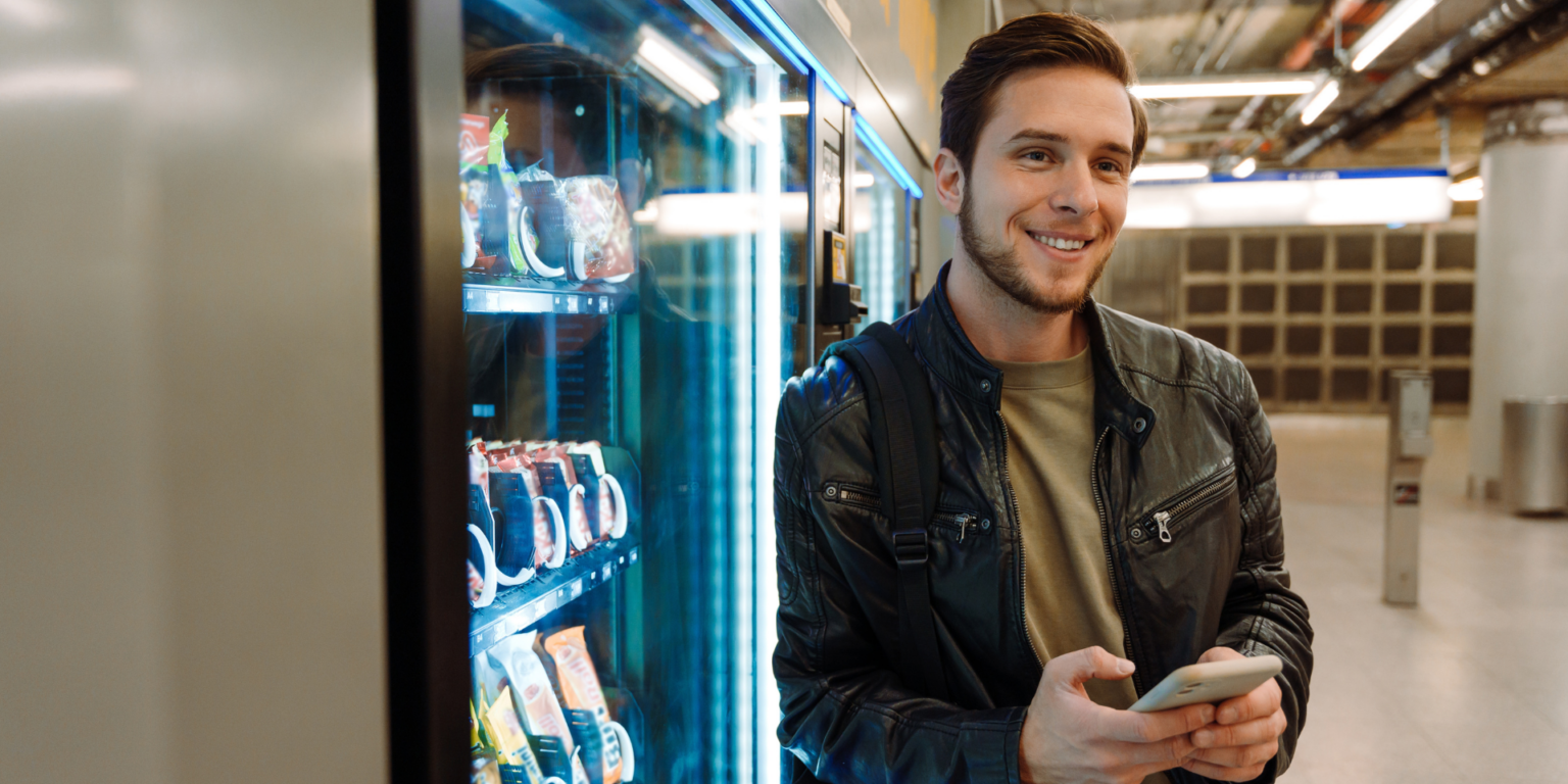 man smiling next to vending machine