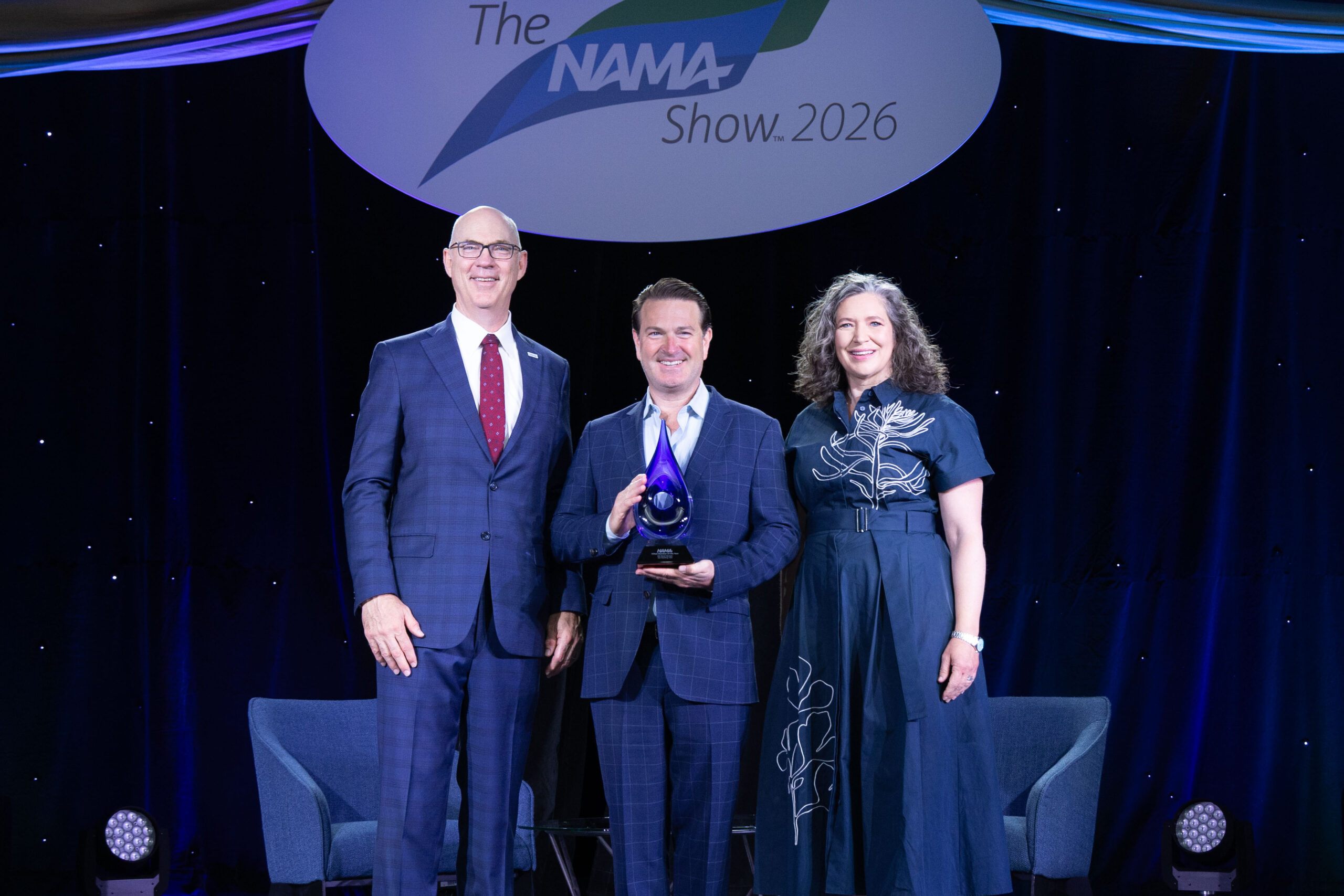 Allied Member of the Year representative standing in the middle of NAMA Board Chair and NAMA CEO accepting award.