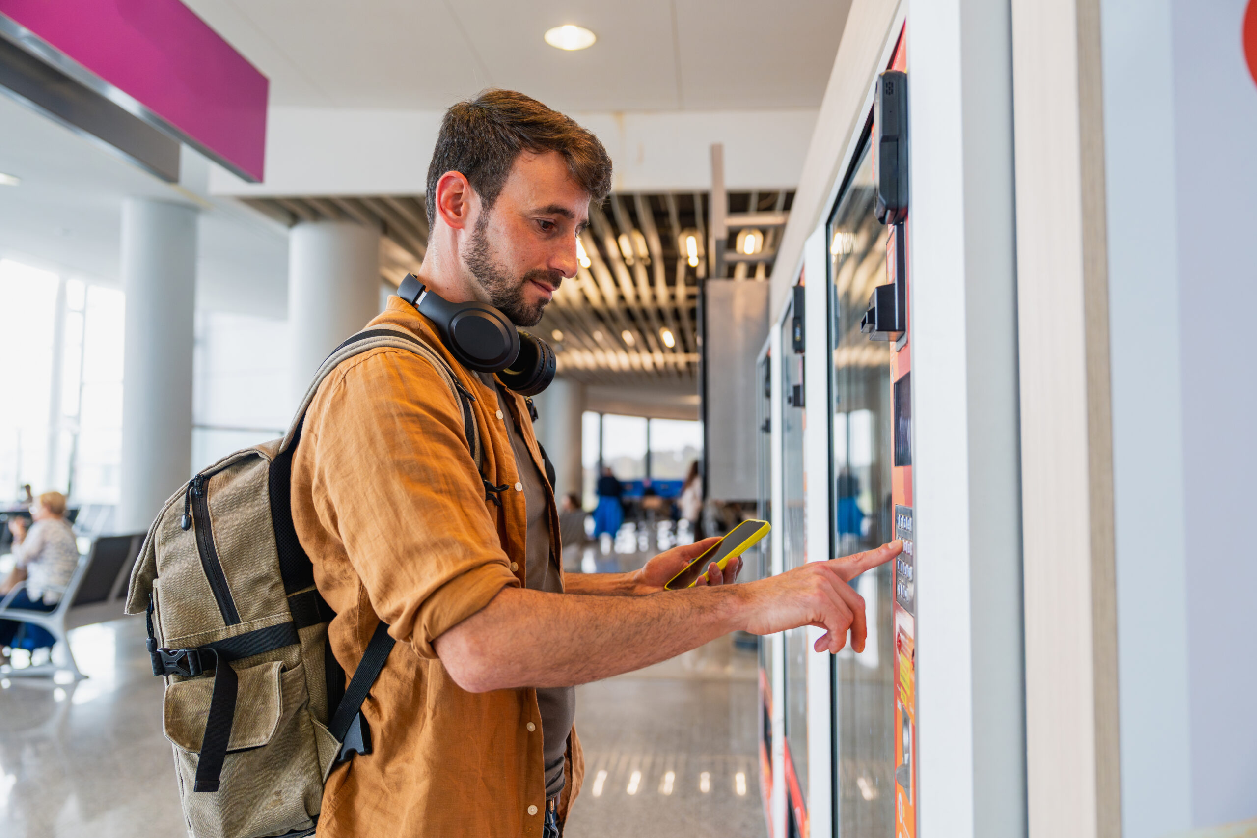 man uses vending kiosk at an airport