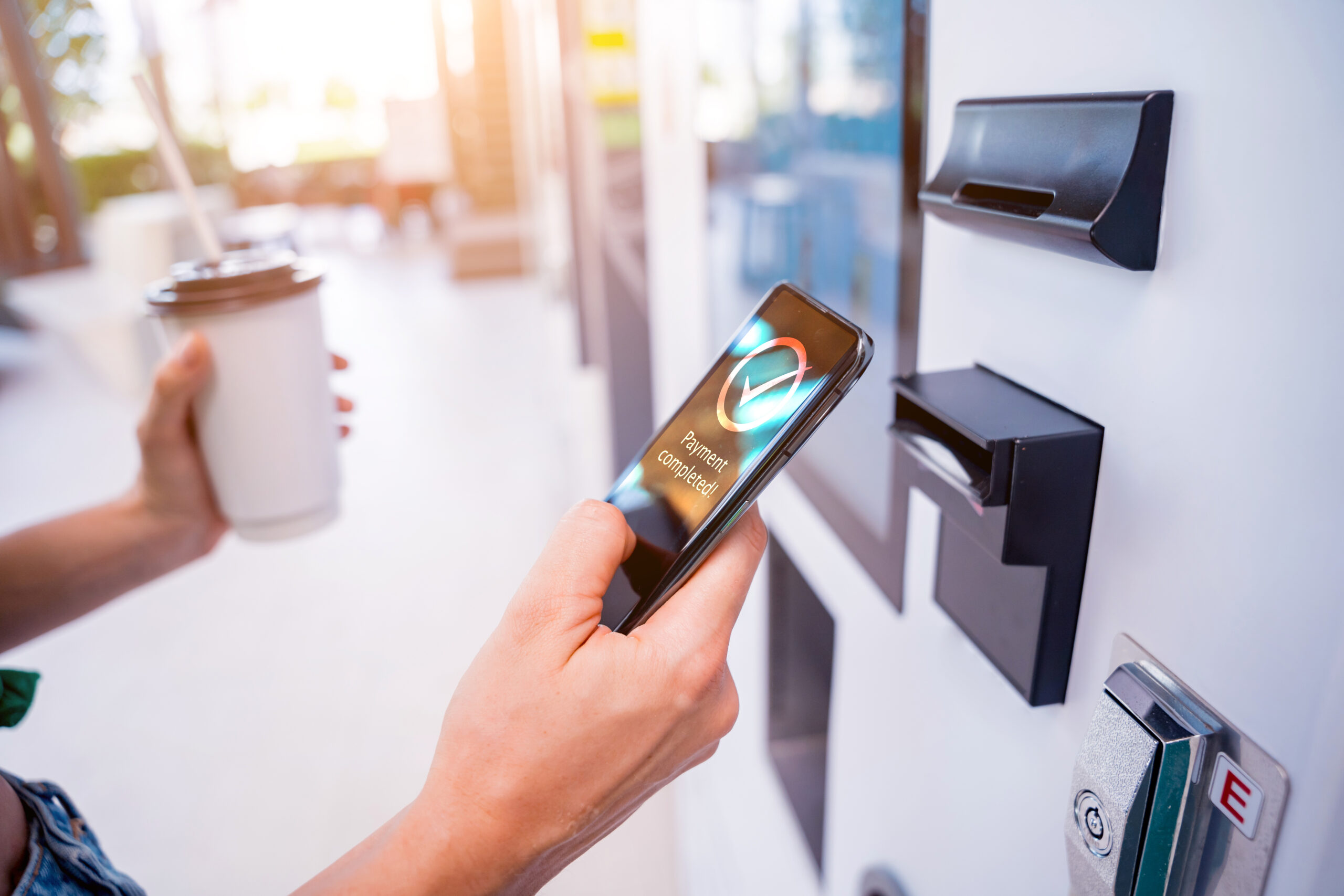 hand holding a phone in front of a kiosk showing successful mobile payment