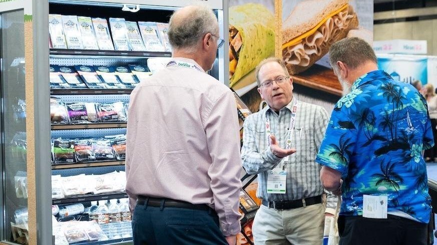 man speaking to two other men in front of a micro market