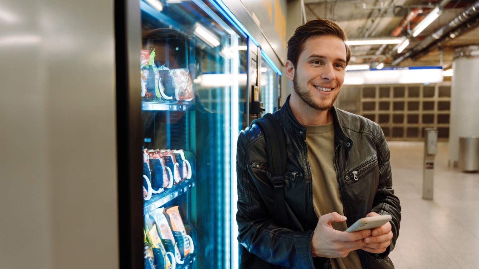 man smiling next to vending machine